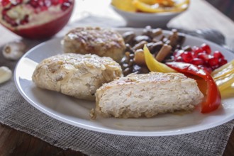 Meatballs with rice mushrooms, sweet peppers and pomegranate seeds on brown wooden background.