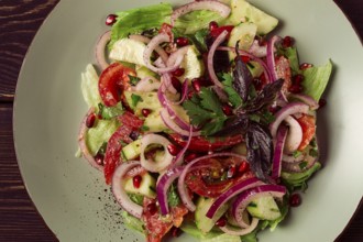 Georgian vegetable salad, tomatoes with cucumbers, red onion, walnut, pomegranate seeds, top view,