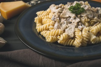 Fusilli pasta, with champignons in cream sauce, top view, with ingredients, on a wooden table, no