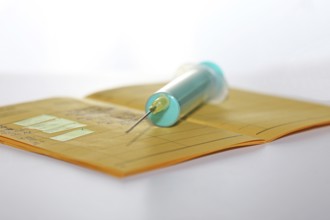 Symbolic image of vaccine with vaccination card and syringe