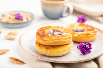 Small cheesecakes with jam and almonds with cup of coffee on a white concrete background and linen