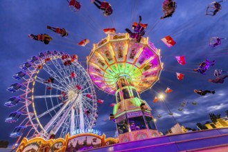 Chain carousel and Ferris wheel in the evening. 177th Cannstatter Volksfest at the Cannstatter