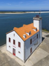 A lighthouse on the coast with a red roof and white façade, Museo Maritimo, surrounded by blue