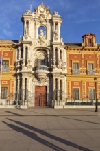 Opulent baroque façade with ornate elements appears in the golden light of the evening sun, Seville