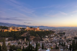 Alhambra and panorama of the city at sunset, surrounded by mountains, Granada