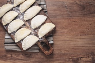 Traditional Polish dish, dumplings, raw, frozen, on a cutting board, wooden table, top view, no