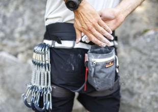 A climber uses so-called chalk (magnesium) in front of climbing a route on the rock, in Morsbach,