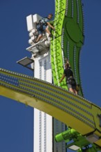 Two employees working high up on the Chaos Pendulum ride, Cranger Kirmes, Herne, Ruhr area, North