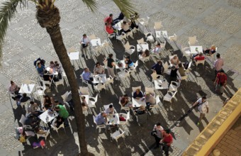 Looking form overhead down on people at restaurant tables in Plaza de la Catedral, Cadiz, Spain,