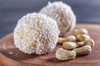 Energy balls cakes with coconut and cashew on wooden board on black background. selective focus,