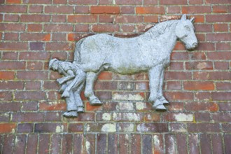 Old sign for farrier and horse on brick wall, Brandeston, Suffolk, England, UK