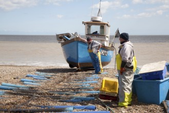 Small inshore fishing boat landing on the beach after six hours at sea with a catch of cod and