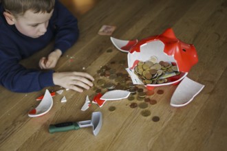 Symbolic photo on the subject of saving. A boy smashes his savings slip and counts the money it