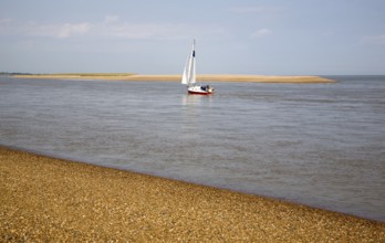 Sailing boat at the mouth of the River Ore at the tip of Orford Ness shingle spit, North Weir