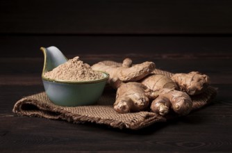 Gemahlene und frische Ingwerwurzel, auf einem Holztisch, rustikaler Stil, selektiver Fokus, keine