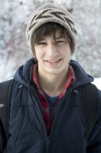 Portrait smiling teenager winter clothes snow background, UK -model released