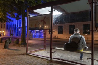 Bus stop, blue illuminated building of the Münster district government, illuminated barrier, in