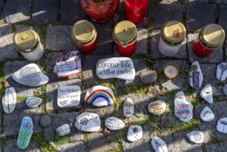 Candles and stones with inscriptions in memory of the dead of the corona pandemic, stickers from