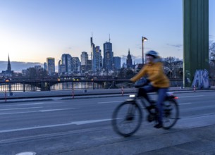 Skyline of the city centre of Frankfurt am Main, cyclist on the raft bridge, dusk, river Main,