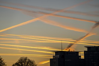 Condensation trails from aircraft flying at high altitude, evening sky, after sunset