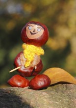 Chestnut figure with yellow scarf and leaves on tree trunk, North Rhine-Westphalia, Germany, Europe