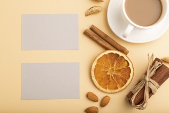 Composition of gray paper business cards, almonds, cinnamon and cup of coffee. mockup on orange