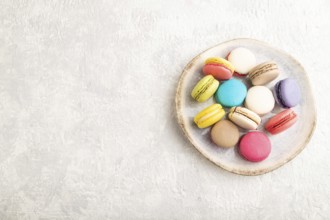 Multicolored macaroons on ceramic plate on gray concrete background. top view, copy space, still