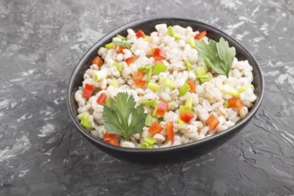 Pearl barley porridge with vegetables in blue ceramic bowl on a black concrete background. side