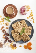 Homemade granola from oat flakes, dates, dried apricots, raisins, nuts in blue ceramic plate with a