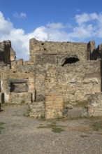 Remnants of old terracotta brick and stone wall structures with rectangular and arched openings at