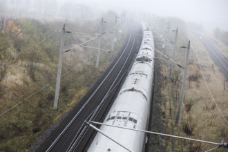 A Deutsche Bahn ICE train runs in foggy autumn weather on a railway line near Neugarten, 06.11