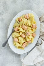 Papardelle pasta, in creamy sauce with salmon, natural light, lifestyle, homemade, on a gray