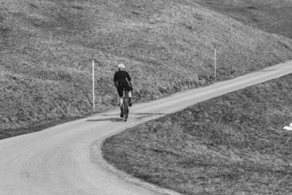 Road bike rider in spring in the Allgäu against the picturesque backdrop of the Alps, Bavaria,