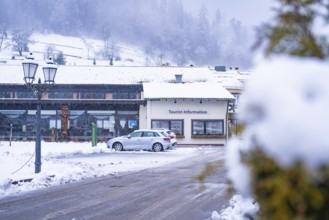 Tourist information centre with parked cars, in front of a snowy mountain scenery, Enzklösterle,