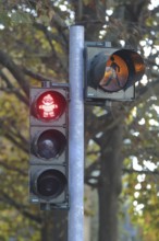 Red pedestrian traffic light with orange flashing light and Mainzelmännchen as symbol to stand,