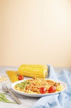 Corn noodles with tomato sauce and arugula on a gray and orange background and blue textile. Side