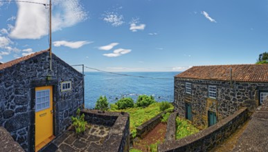 Rustic lava stone houses against a picturesque sea backdrop, fishing village, Sao Joao, Pico