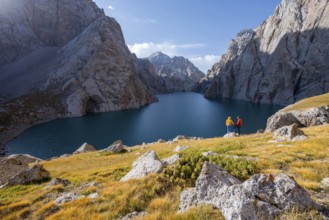 Tourists, couple at the blue mountain lake between rocky steep mountain peaks, Kol Suu Lake, Sary