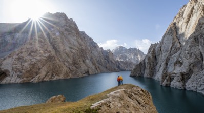 Couple at the blue mountain lake between rocky steep mountain peaks, Sun Star, Kol Suu Lake, Sary