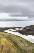 Two hikers on a hill in the distance, colourful volcanic landscape with hills and snow, Laugavegur