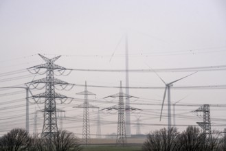 Wind farm in the fog, high-voltage pylons, dark doldrums, no wind no direct sunlight, in the