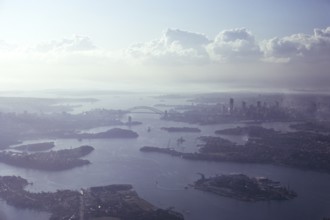 Oblique aerial view of the harbour, the bridge and the city centre skyline, Sydney, Australia 1974