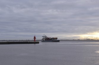 Container ship Beate sails on the Elbe at sunset and turns into the Brunsbüttel lock to the Kiel