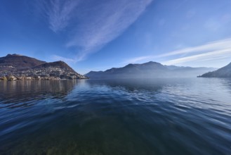 Lake, hill with village, haze, fog, blue sky with cirrostratus clouds, Lake Lugano, Lugano,