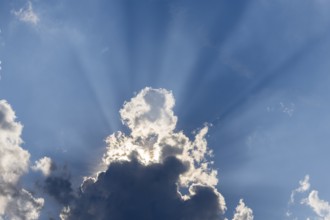 Rain clouds with sun shining through, rays of sunshine, blue sky