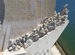 Close-up of a row of statues placed at a monument on a sunny day along the coast, aerial view,