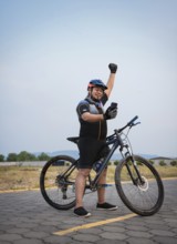 Professional cyclist looking happily at the cell phone in the street. Cyclist in sport suit using