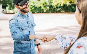 Young man and girl shaking fists in the street. A guy and girl shaking hands on the street. Two