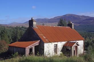 An old farmhouse with a rusty roof in a remote mountain landscape, autumn, October, Highlands,