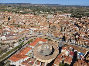 Aerial view of a historic town with tiled roofs and a central square in the middle of a hilly